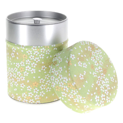 photo packshot d'une boîte à thé cylindrique ouverte tapissée de papier japonais aux motifs de fleurs au vent vert amande (M984) adeline klam