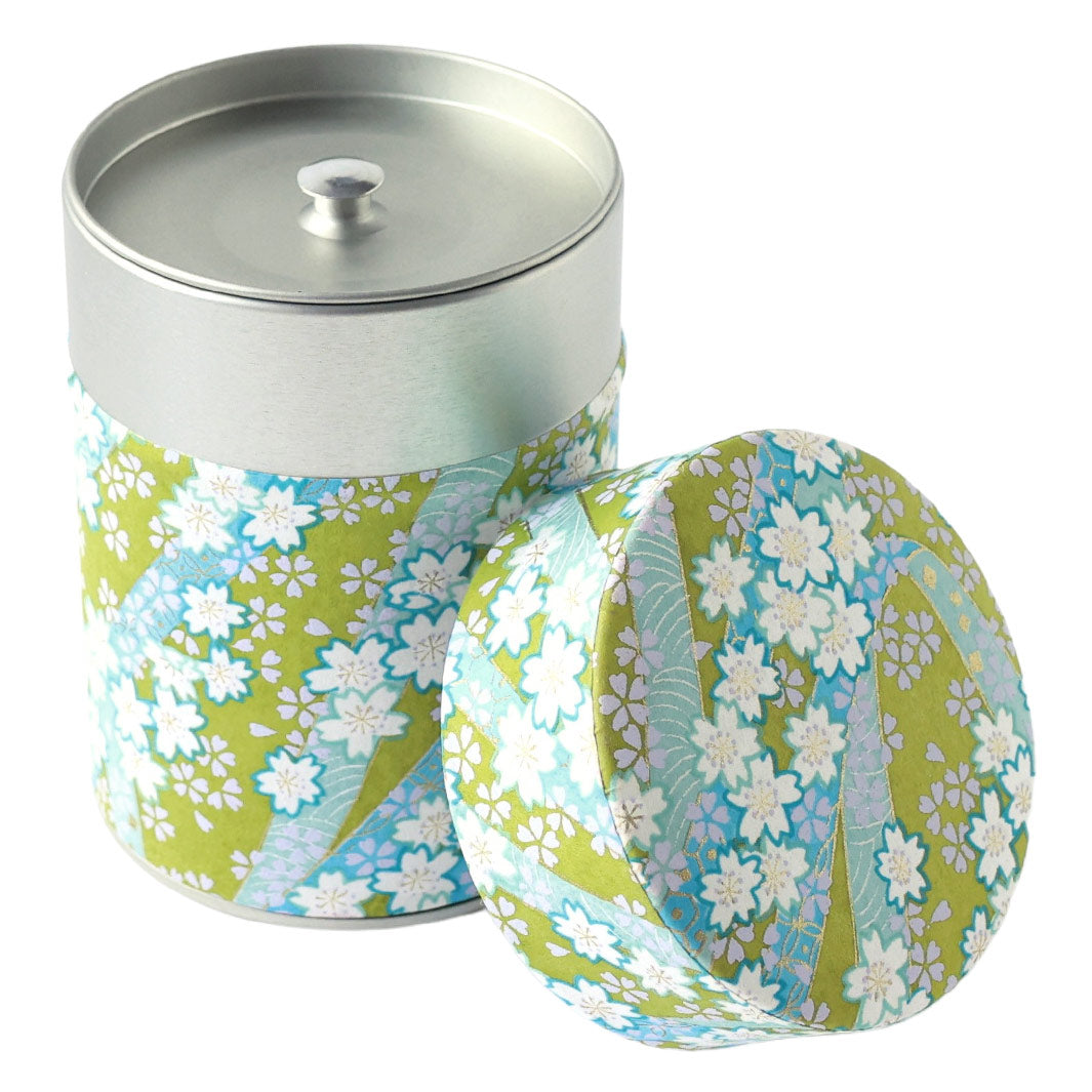 photo packshot d'une boîte à thé cylindrique ouverte tapissée d'un papier japonais aux motifs d'ondulations fleuries jaune vert, bleu mauve, vert d'eau, lilas et dorées (M1001) adeline klam