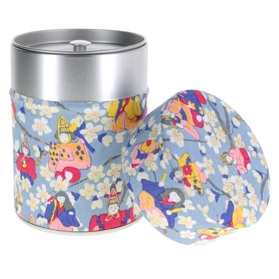 photo packshot d'une boîte à thé cylindrique ouverte tapissée de papier japonais aux motifs de poupées d'hina matsuri et de fleurs de pêcher bleu gris, rose rouge, bleu violet, rose clair et jaune (M1005) adeline klam