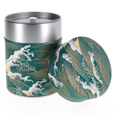 photo packshot d'une boîte à thé cylindrique ouverte tapissée de papier japonais aux motifs de vagues et d'écumes bleu canard, beiges et dorés (M941) adeline klam