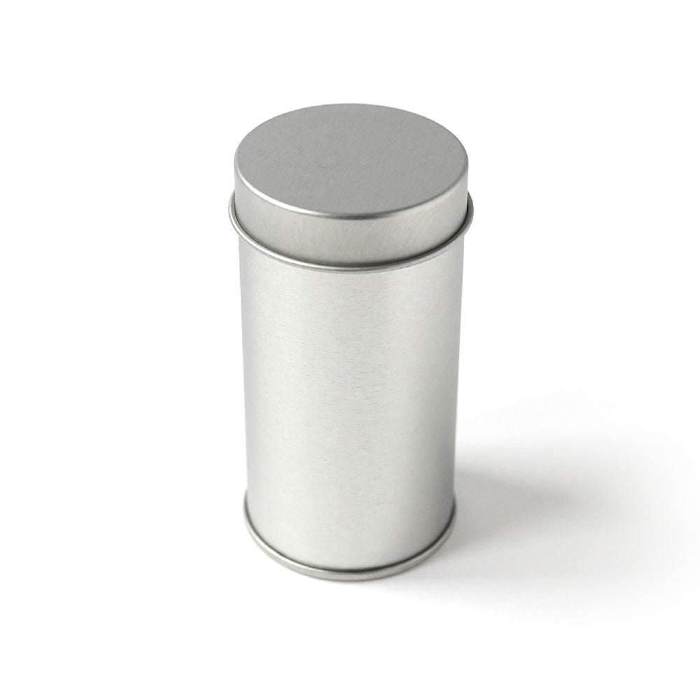 photo packshot d'une mini boîte à thé en métal nue de forme cylindrique posée débout et fermée