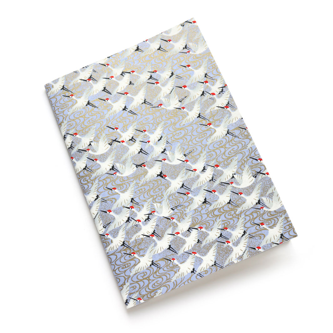 photo packshot d'un carnet habillé de papier japonais aux motifs d'envolée de grues blanches sur fond bleu gris lavande (M388) adeline klam