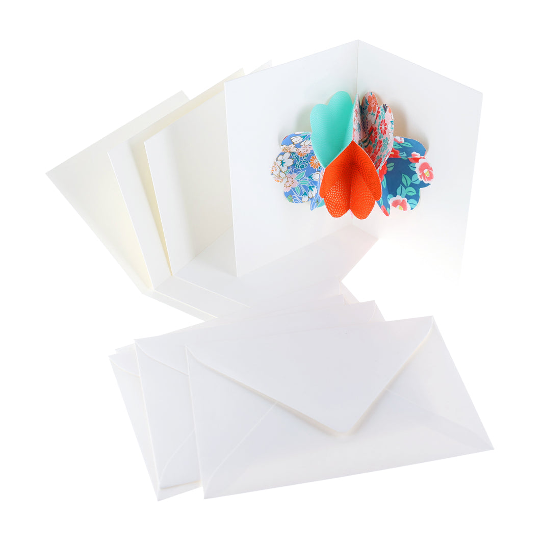 photo packshot d'une carte montée, des cartes doubles vierges et des enveloppes du kit 4 cartes pop-up dans les tons bleu turquoise, vert d'eau, roses et rouge orange « lagune » adeline klam