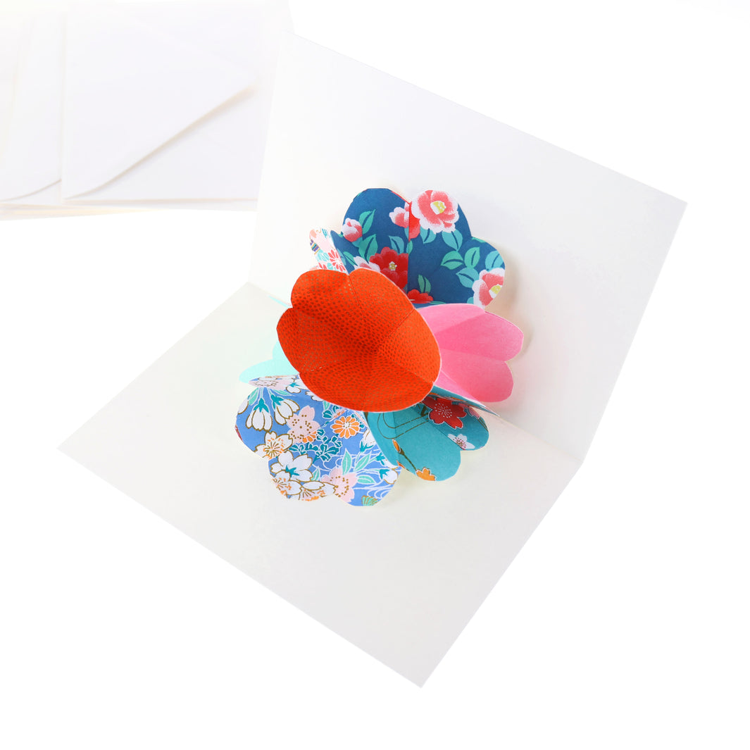 photo packshot d'une carte montée et d'une enveloppe du kit 4 cartes pop-up dans les tons bleu turquoise, vert d'eau, roses et rouge orange « lagune » adeline klam