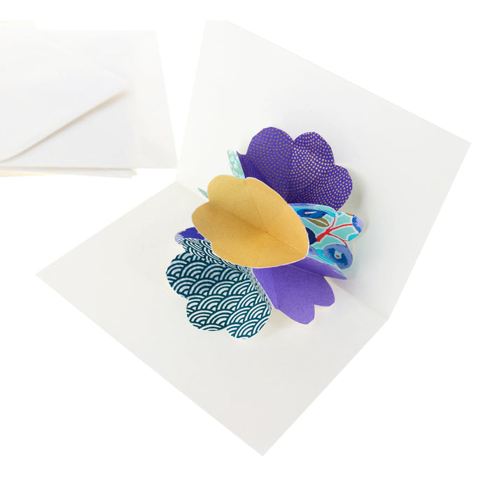 photo packshot d'une carte montée et d'une enveloppe du kit 4 cartes pop-up dans les tons vert d'eau, bleu foncé, violets et dorés « fraîcheur » adeline klam