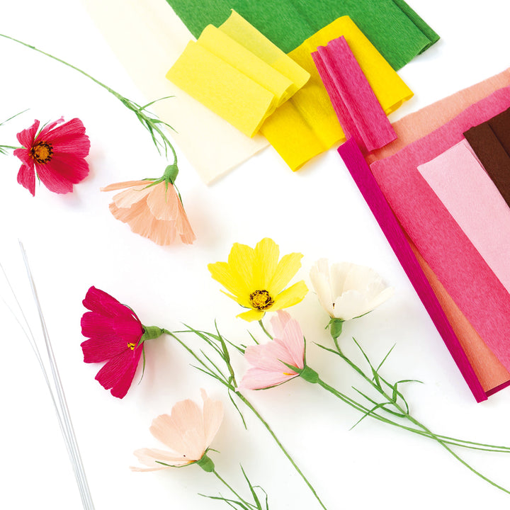 photo packshot des cosmos réalisés posés à plat et du matériel du kit bouquet de cosmos en crépon dans les tons rose clair et foncé, corail, jaune et vert moyen adeline klam