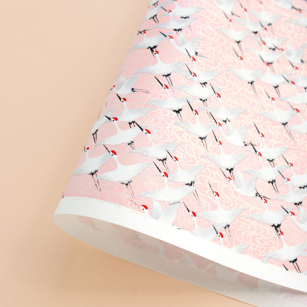photo packshot d'une courbe du papier japonais yuzen chiyogami aux motifs d'envolées de grues blanches sur fond rose pâle adeline klam (M662)