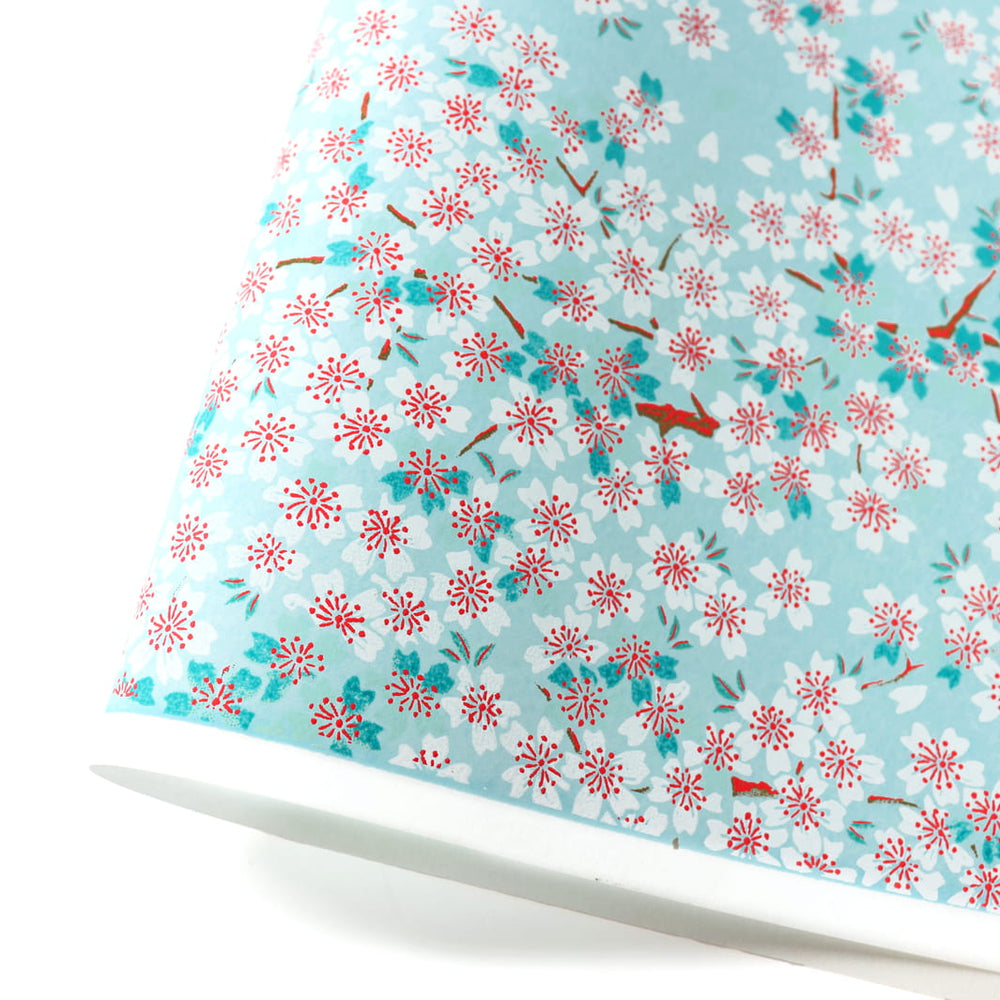 photo packshot d'une courbe de papier japonais yuzen chiyogami au motif de fleurs de cerisier dans les tons bleu ciel, bleu turquoise, rouges et blancs adeline klam (M580)
