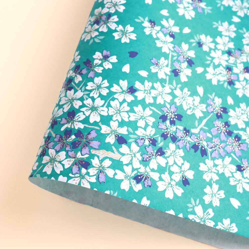 photo packshot d'une courbe de papier japonais yuzen chiyogami au motif de fleurs de cerisier dans les tons bleu turquoise, bleu marine, gris violet et blanc adeline klam (M625)