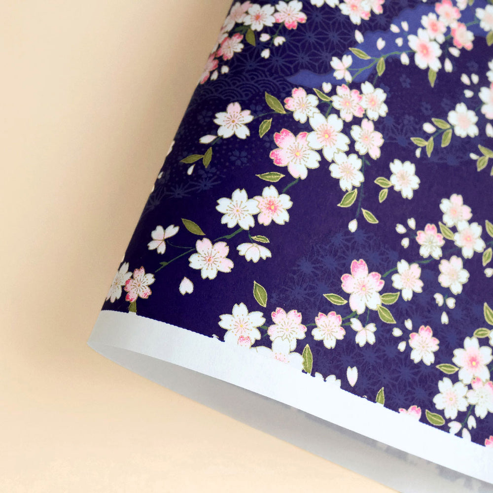 photo packshot d'une courbe de papier japonais yuzen chiyogami aux motifs de fleurs de cerisier et de motifs variés sur fond bleu violet foncé adeline klam (M734)