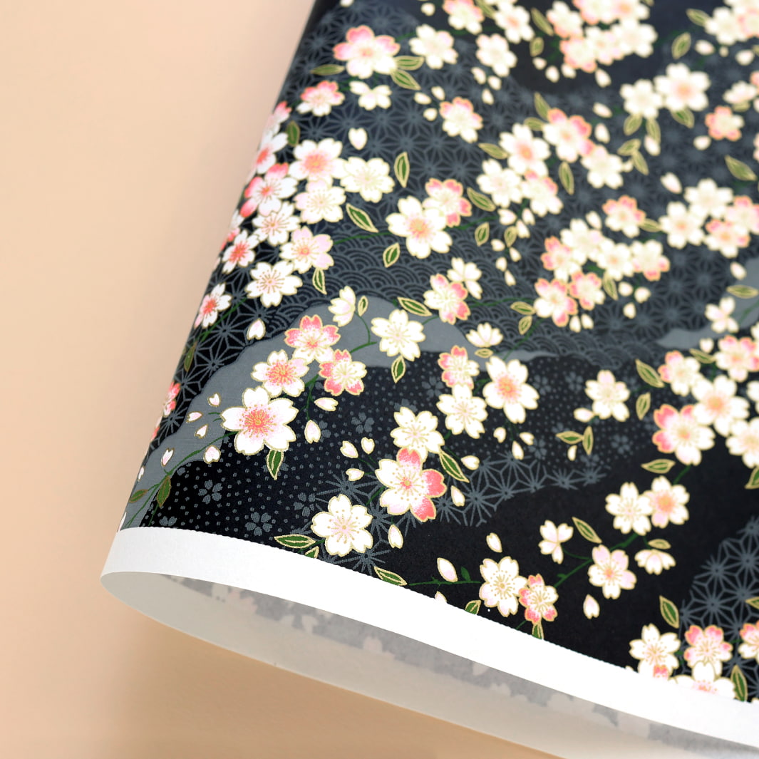 photo packshot d'une courbe de papier japonais yuzen chiyogami aux motifs de fleurs de cerisier et de motifs variés sur fond noir adeline klam (M886)
