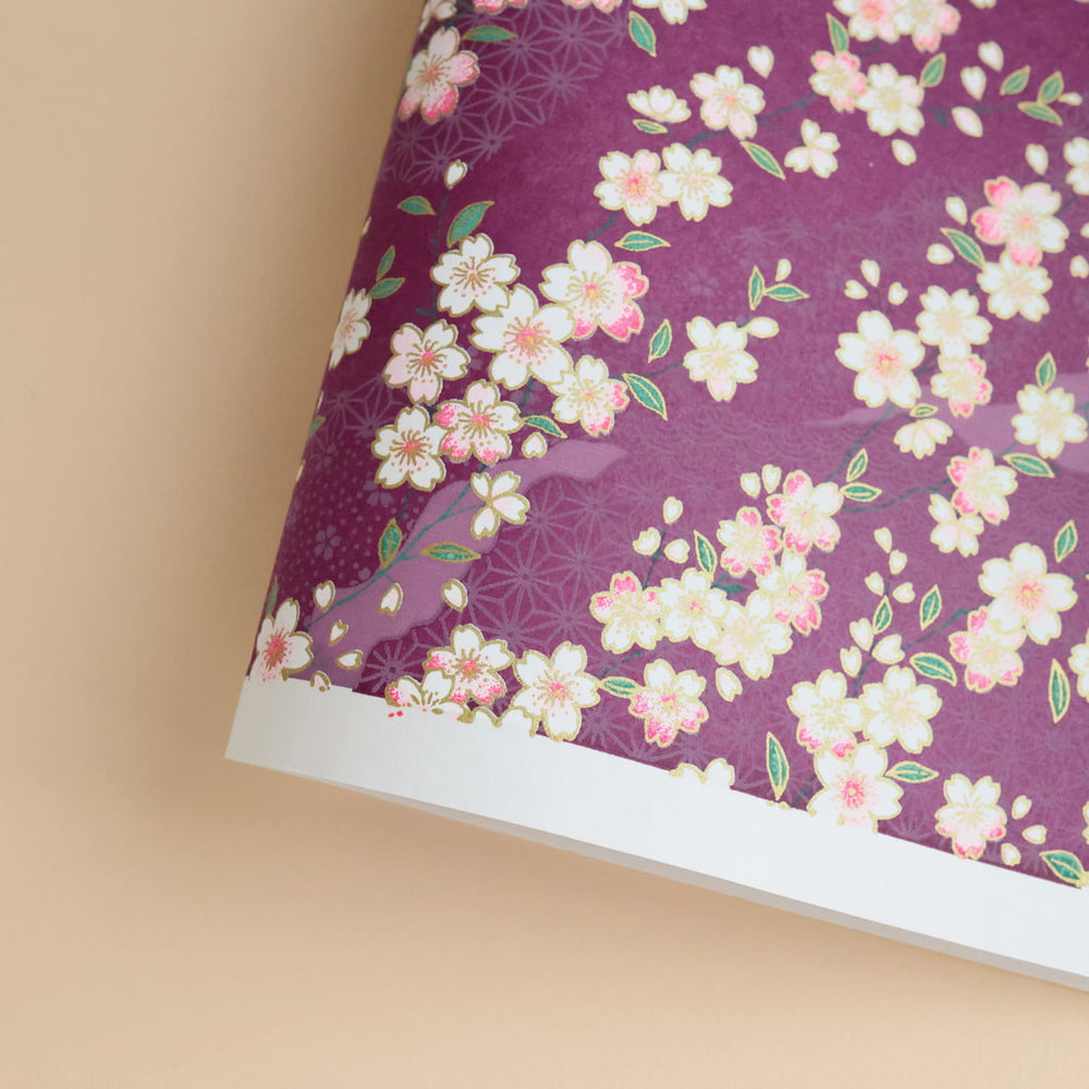 photo packshot d'une courbe de papier japonais yuzen chiyogami aux motifs variés et de fleurs de cerisier sur fond violet prune adeline klam (M383)