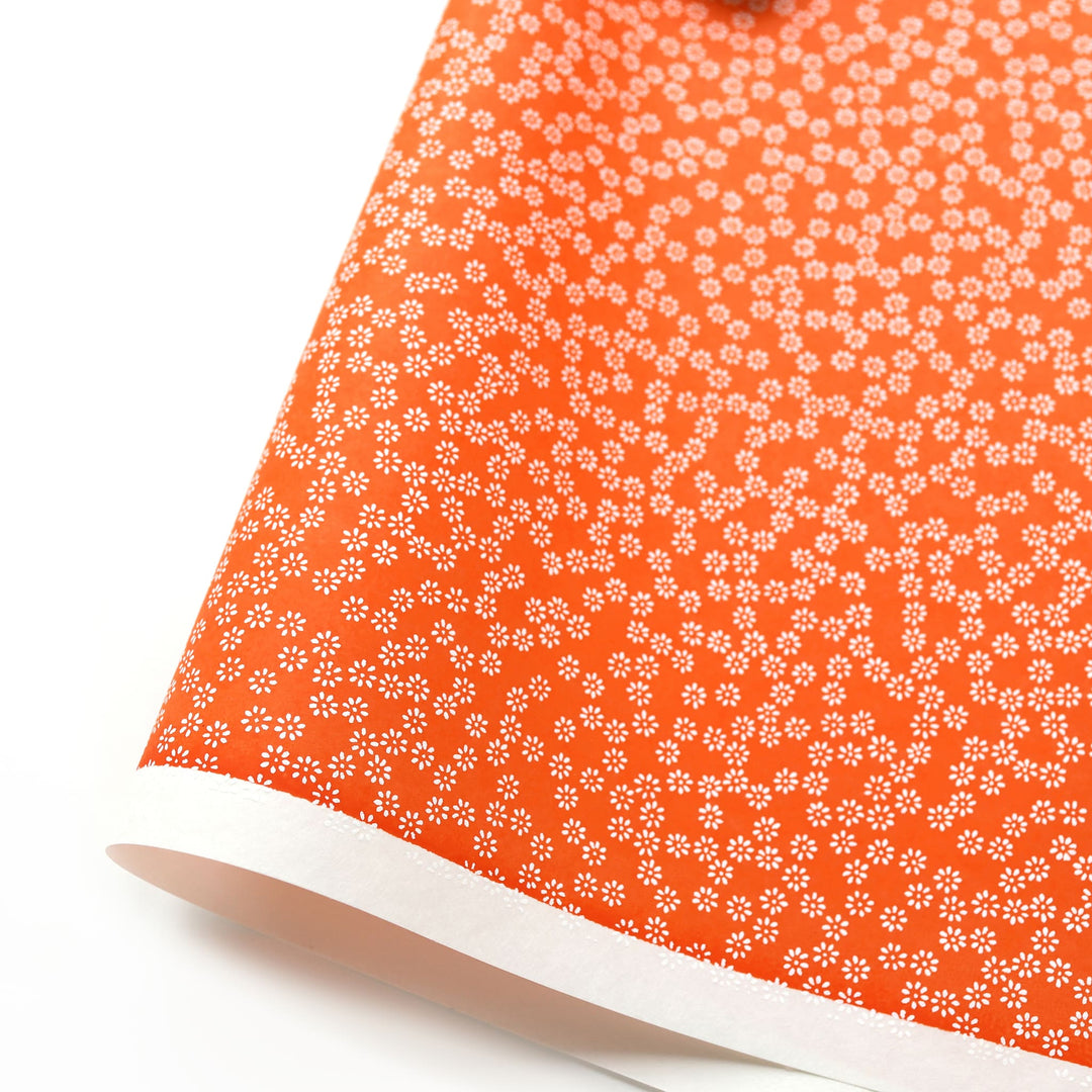 photo packshot d'une courbe de papier japonais yuzen chiyogami aux motifs de semi de fleurs blanches sur fond orange rouge adeline klam (M1069)