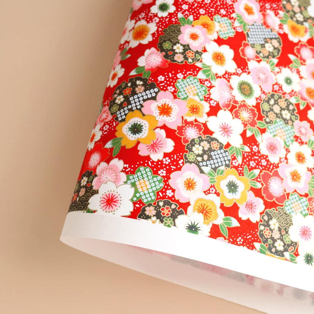 photo packshot d'une courbe de papier japonais yuzen chiyogami aux motifs de fleurs de cerisier traditionnelles blanches, roses, jaunes et vertes sur fond rouge adeline klam (M368)