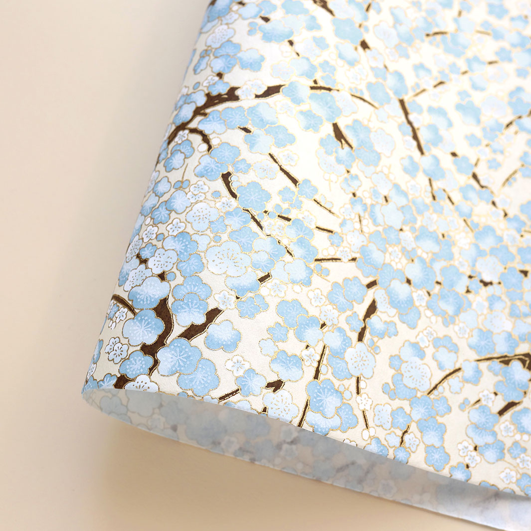 photo packshot d'une courbe de papier japonais yuzen chiyogami aux motifs de fleurs de prunier dans les tons blanc crème, bleu clair et marron foncé adeline klam (M434)