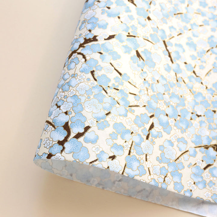 photo packshot d'une courbe de papier japonais yuzen chiyogami aux motifs de fleurs de prunier dans les tons blanc crème, bleu clair et marron foncé adeline klam (M434)