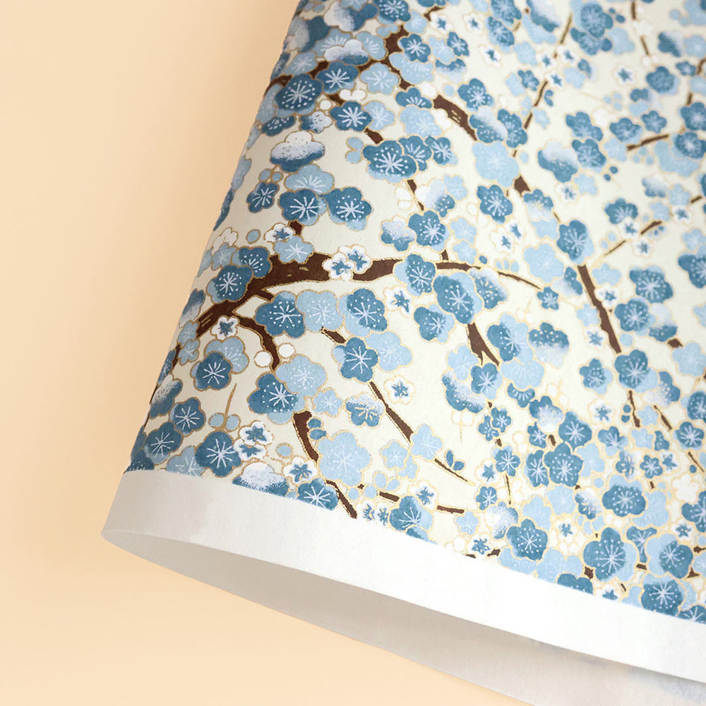 photo packshot d'une courbe de papier japonais yuzen chiyogami aux motifs de fleurs de prunier dans les tons bleu clair et foncé, crème adeline klam (M425)