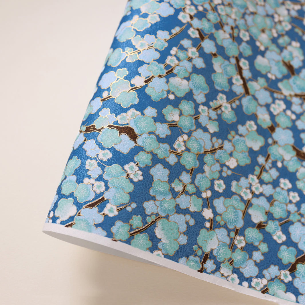 photo packshot d'une courbe de papier japonais yuzen chiyogami aux motifs de fleurs de prunier dans les tons bleu foncé, bleu ciel et vert d'eau adeline klam (M448)