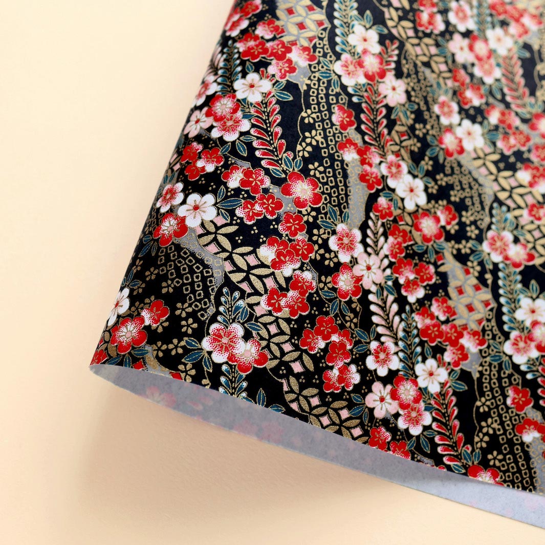 photo packshot d'une courbe de papier japonais yuzen chiyogami aux motifs de fleurs de prunier et de nuages à motifs dans les tons rouges, roses, noirs, bleu canard et dorés adeline klam (M1019)