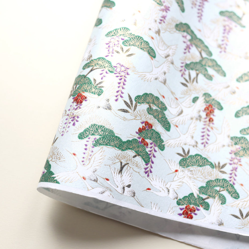 photo packshot d'une courbe de papier japonais yuzen chiyogami aux motifs de grues et de forêts sur fond bleu pâle adeline klam (M657)