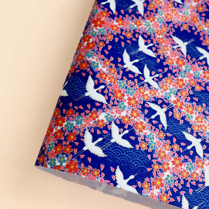photo packshot d'une courbe de papier japonais yuzen chiyogami aux motifs de grues, de vagues et de fleurs dans les tons bleu foncé et turquoise, rouges, roses et blancs adeline klam (M876)