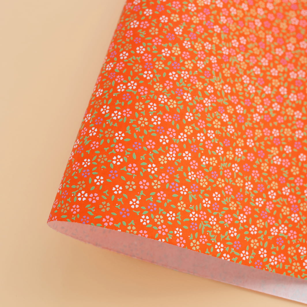 photo packshot d'une courbe de papier japonais yuzen chiyogami aux motifs de mini fleurs de cerisier dans les tons rouge orange adeline klam (M663)