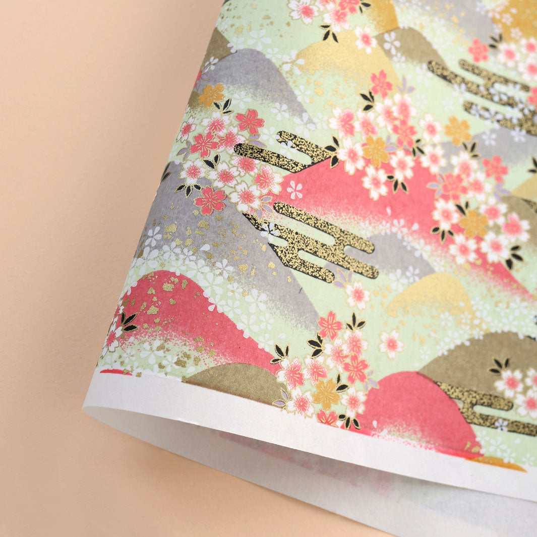 photo packshot d'une courbe de papier japonais yuzen chiyogami aux motifs de montagnes et de fleurs de cerisier dans les tons bois de rose, jaune moutarde, vert amande, gris et dorés adeline klam (M1033)