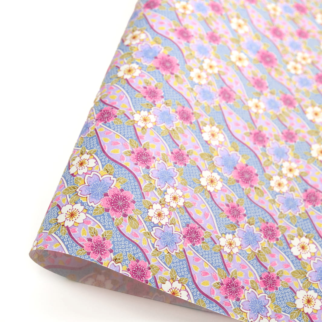 photo packshot d'une courbe de papier japonais yuzen chiyogami aux motifs d'ondulations fleuries de cerisier et de petits losanges kanoko dans les tons lilas, mauve, bleus et jaunes adeline klam (M1050)