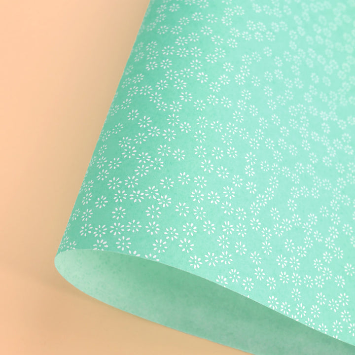 photo packshot d'une courbe de papier japonais yuzen chiyogami aux motifs de semi de fleurs blanches sur fond vert d'eau adeline klam (M505)