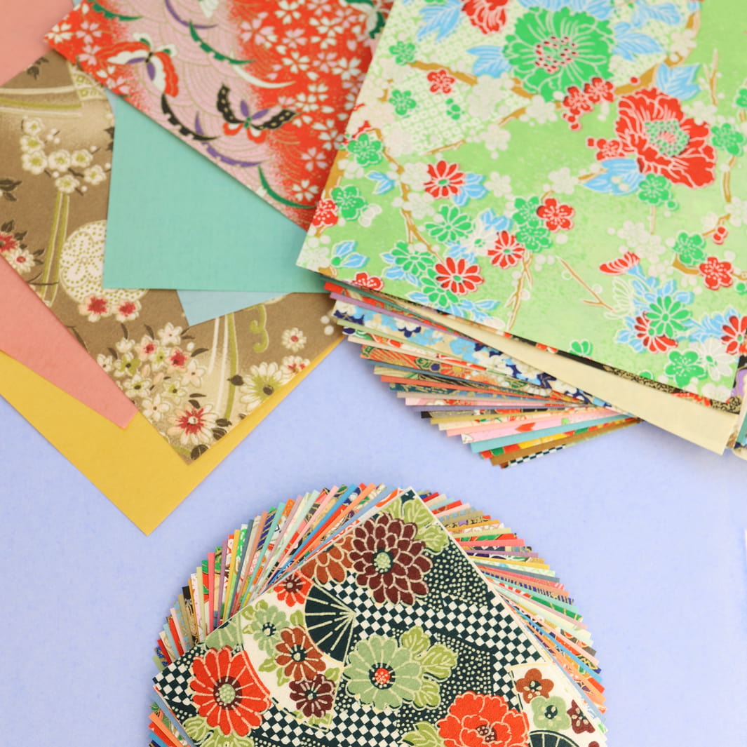 photo packshot d'un détail de l'assortiment de papiers du set de 40 papiers origami en 10cm par 10cm aux motifs traditionnels et unis dans un mélange folklorique furukawashiko