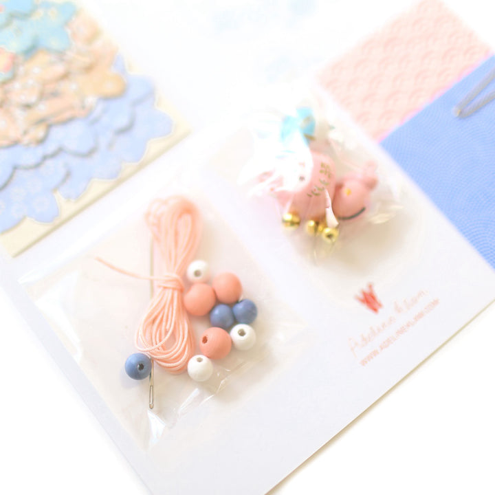 photo packshot du détail du fil, des perles et des grelots du kit guirlande porte-bonheur bleu lavande, rose clair et blancs « givre » adeline klam