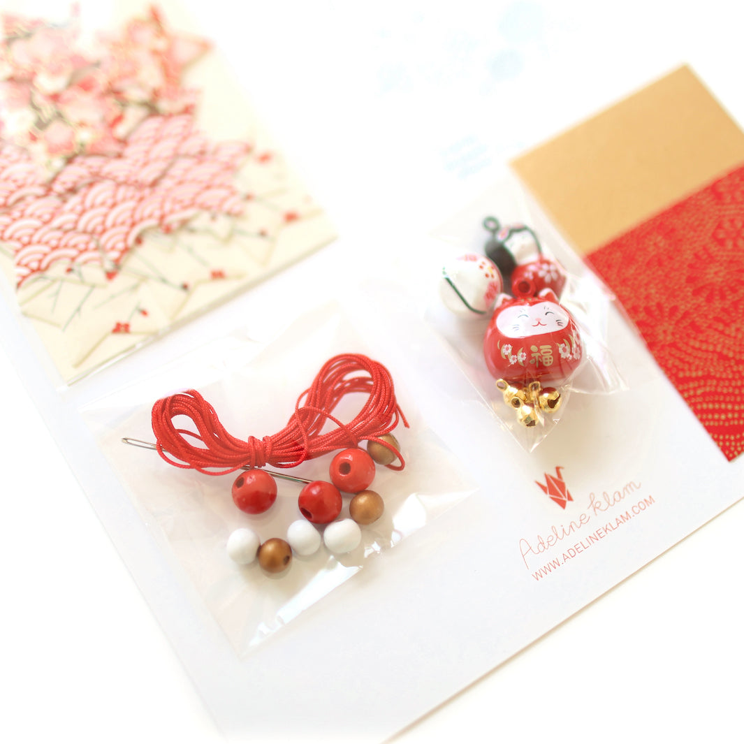 photo packshot du détail du fil, des perles et des grelots du kit guirlande porte-bonheur rouge, blanc et doré « christmas » adeline klam