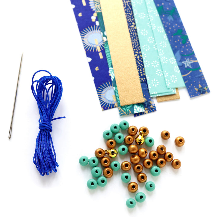 photo packshot d'un détail du matériel du kit guirlande d'étoiles en origami bleu nuit, bleu turquoise, vert, vert d'eau et doré « libellule » adeline klam
