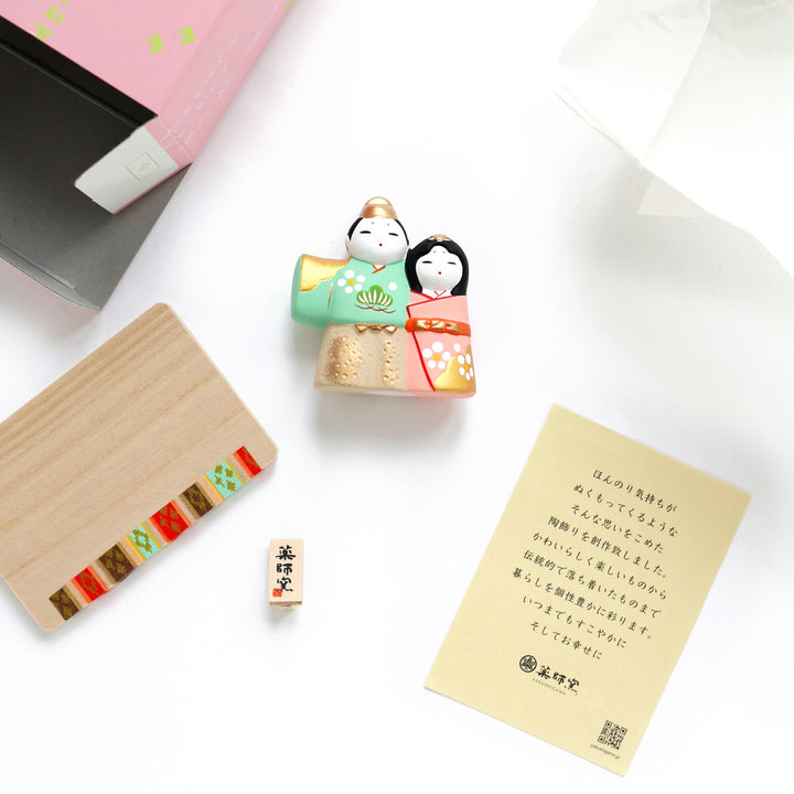 photo packshot du détail du packaging du couple en céramique « hina matsuri » dans les tons vert d'eau, roses et dorés