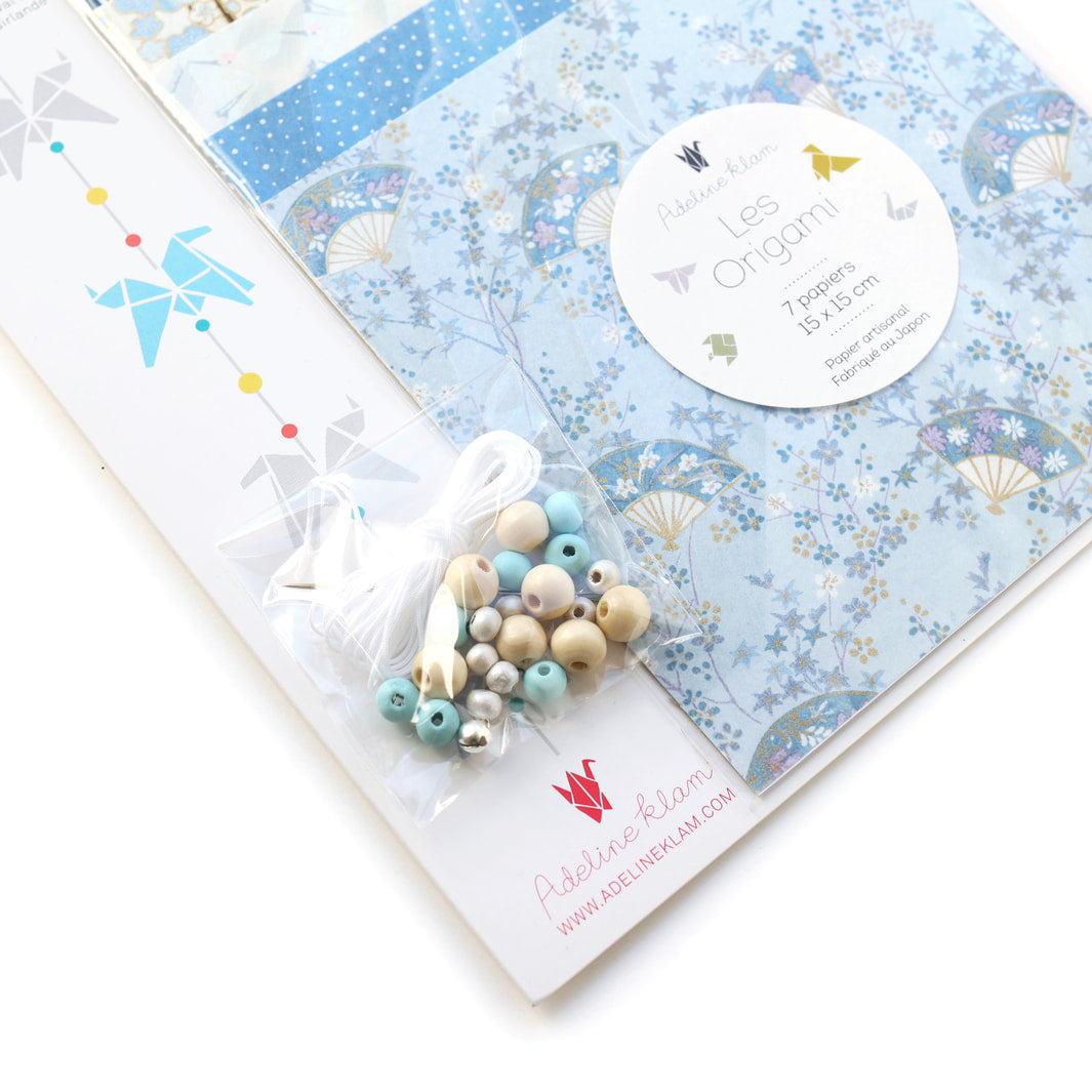 photo packshot d'un détail du packaging du kit guirlande de chevaux en origami dans les tons bleu ciel, bleu gris, blanc crème et blanc nacré « rivage » O4 adeline klam 