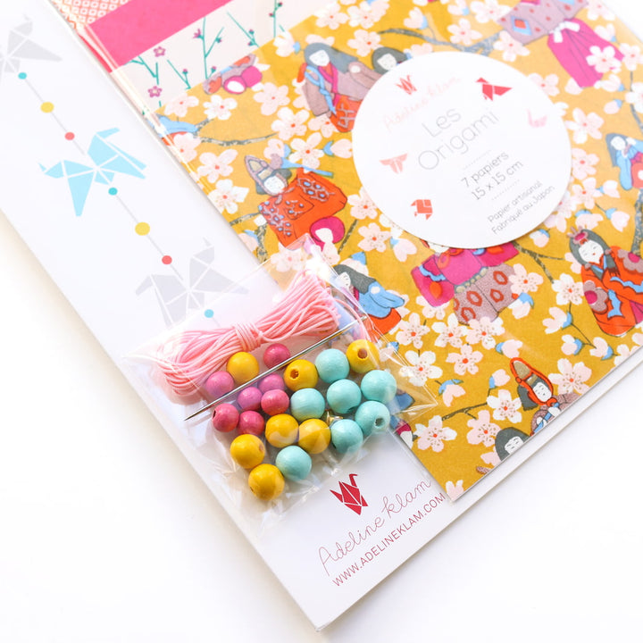 photo packshot d'un détail du packaging du kit guirlande de chevaux en origami dans les jaune moutarde, corail, rose fuchsia et bleu gris « fruité » A14 adeline klam 