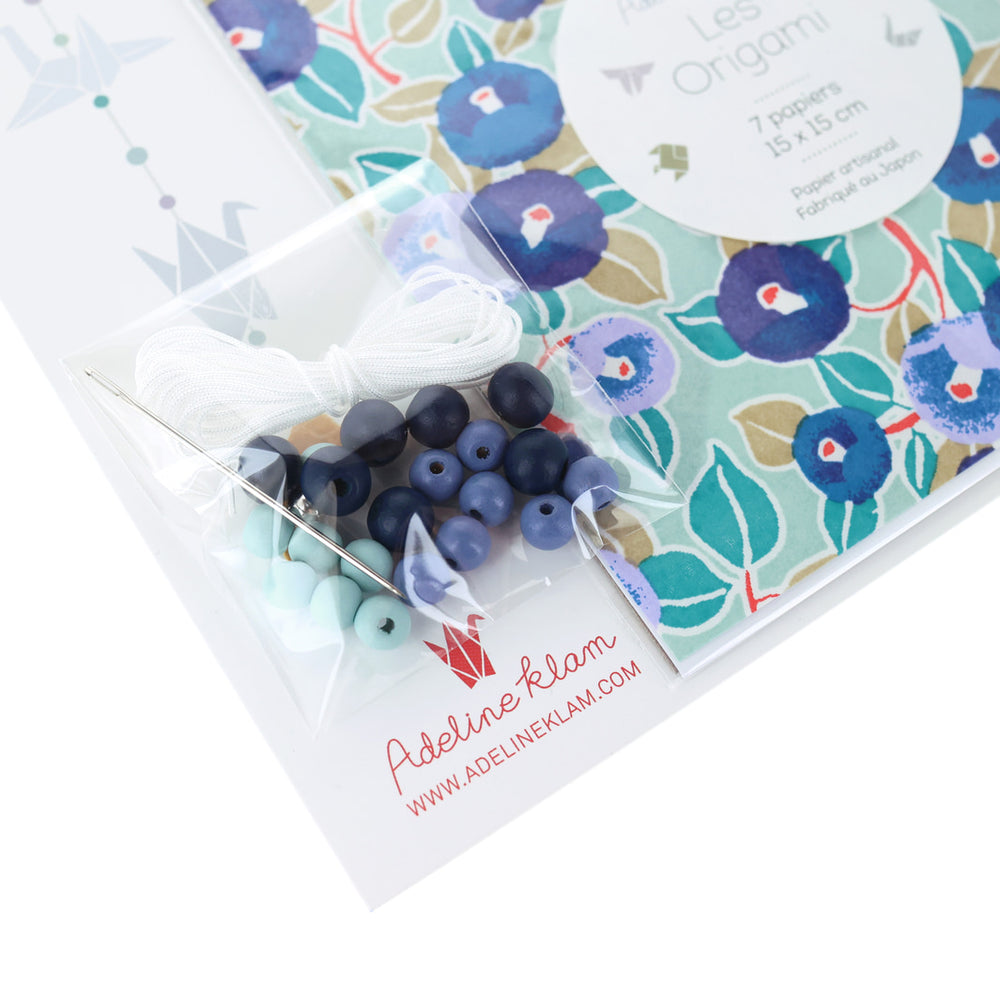 photo packshot d'un détail du packaging du kit créatif guirlande de grues en origami « fraîcheur » (Z14) dans les tons bleu marine, nuit et pervenche, vert d'eau et dorés adeline klam