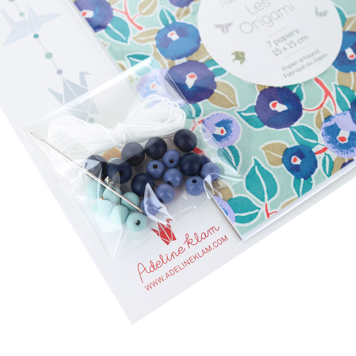 photo packshot d'un détail du packaging du kit créatif guirlande de grues en origami « fraîcheur » (Z14) dans les tons bleu marine, nuit et pervenche, vert d'eau et dorés adeline klam