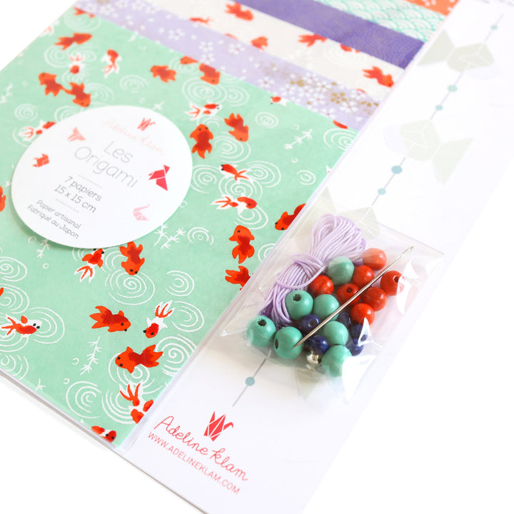 photo packshot d'un détail du packaging du kit guirlande de poissons dans les tons vert d'eau, rouge orange, blanc crème et violet mauve « fluorite » adeline klam