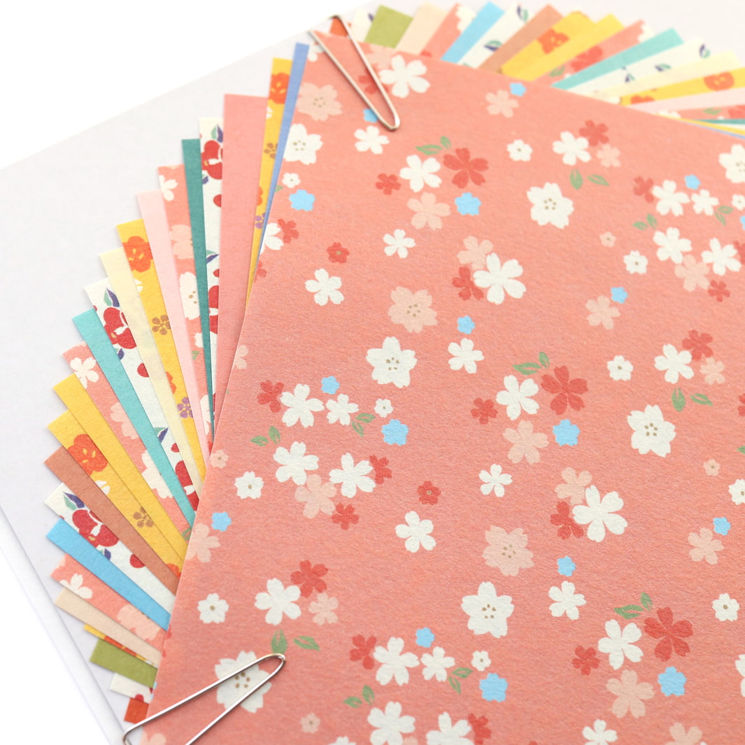 photo packshot d'un détail du packaging du set de 24 papiers origami en 15cm par 15cm aux motifs fleuris et unis dans un mélange hana furukawashiko