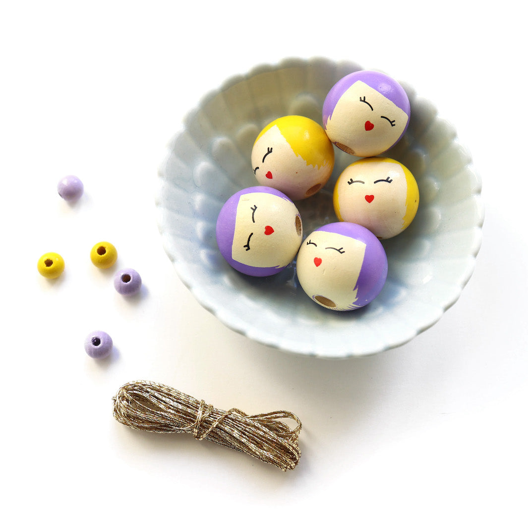 photo packshot d'un détail des perles et des fils du kit anges accordéon jaune moutarde, vert prairie, violets et lilas « primevère » adeline klam