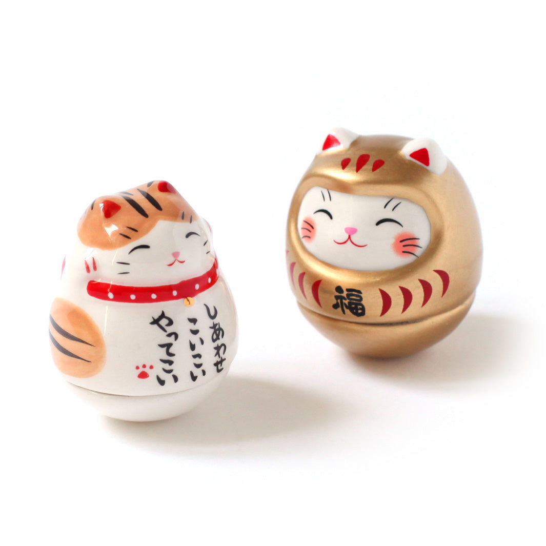 photo packshot de culbutos japonais (ou kororin) en céramique en forme de maneki-neko blanc tigré roux et noir et de daruma chat doré