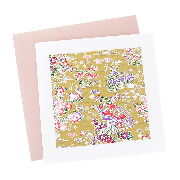 photo packshot vue de face de la carte carrée double habillée d'un carré de papier japonais de 13cm aux motifs d'éventails fleuris dans les tons jaune moutarde, roses, violets et vert foncé (M1048) et son enveloppe rose clair adeline klam