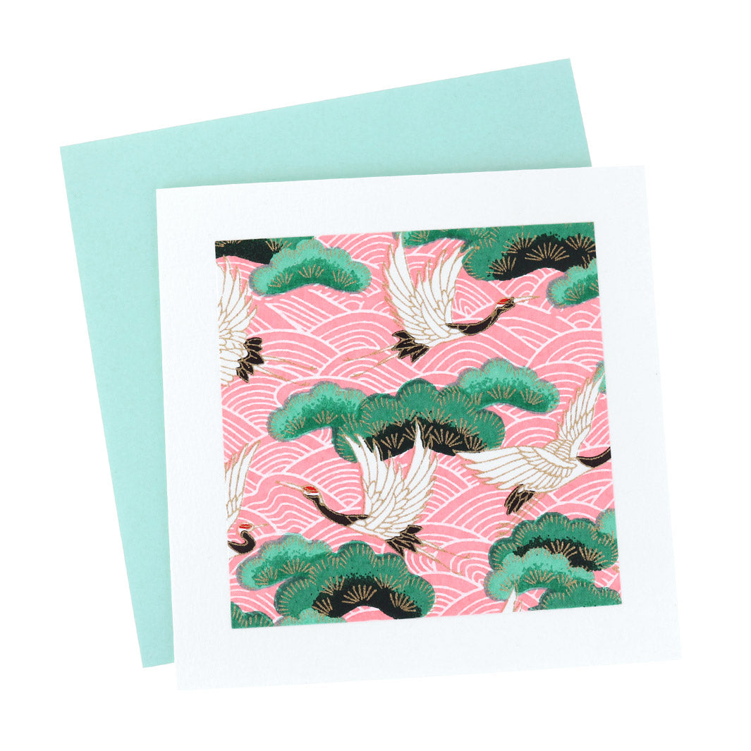 photo packshot vue de face de la carte carrée double habillée d'un carré de papier japonais de 13cm aux motifs de grues, de pins et de vagues blancs, roses et vert (M686) et son enveloppe vert d'eau adeline klam