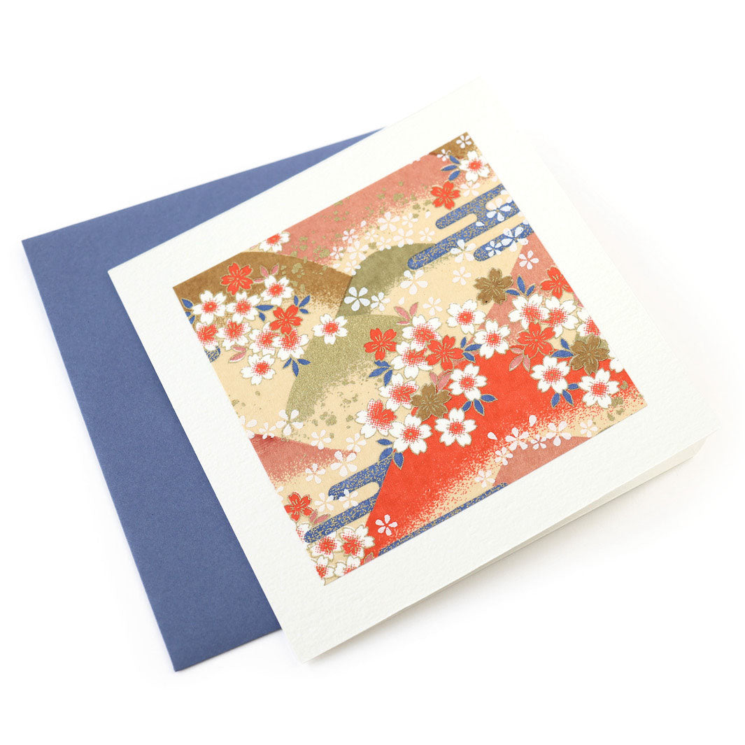 photo packshot vue de face de la carte carrée double habillée d'un carré de papier japonais de 13cm au motifs de montagnes et de fleurs de cerisier dans les tons jaunes, orange, verts et bleus (M761) et son enveloppe assortie adeline klam