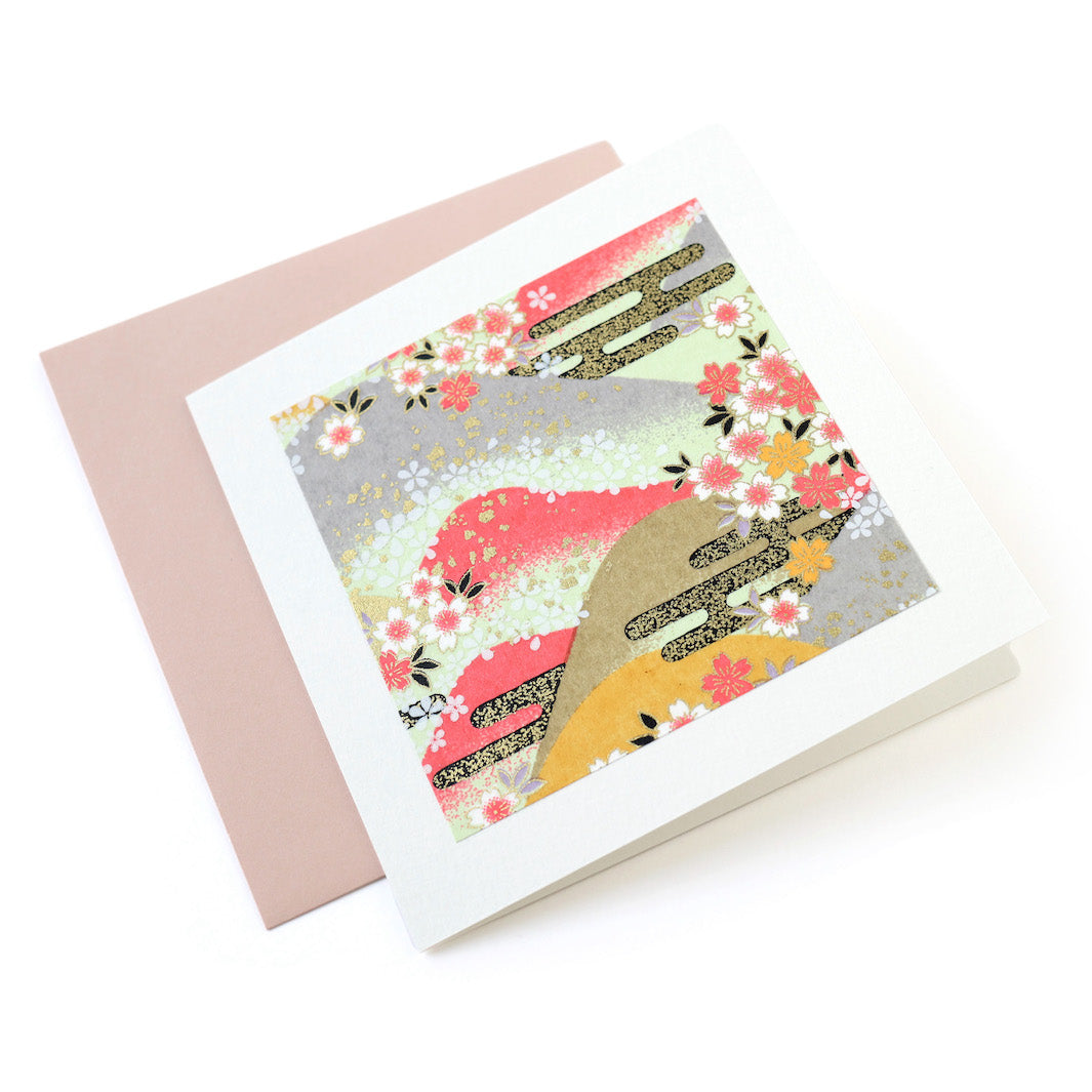 photo packshot vue de face de la carte carrée double habillée d'un carré de papier japonais de 13cm au motifs de montagnes et de fleurs de cerisier dans les tons roses, jaunes, verts, gris et doré (M1033) et son enveloppe assortie adeline klam