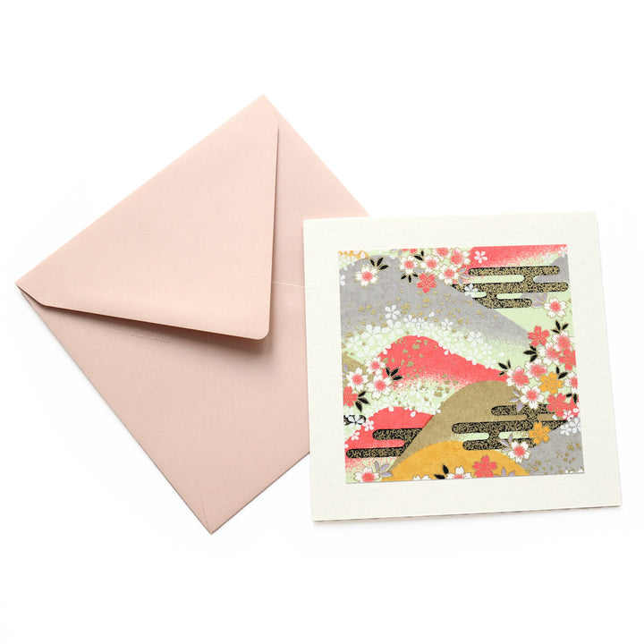 photo packshot vue de face de la carte carrée double habillée d'un carré de papier japonais de 13cm au motifs de montagnes et de fleurs de cerisier dans les tons roses, jaunes, verts, gris et doré (M1033) et son enveloppe assortie adeline klam