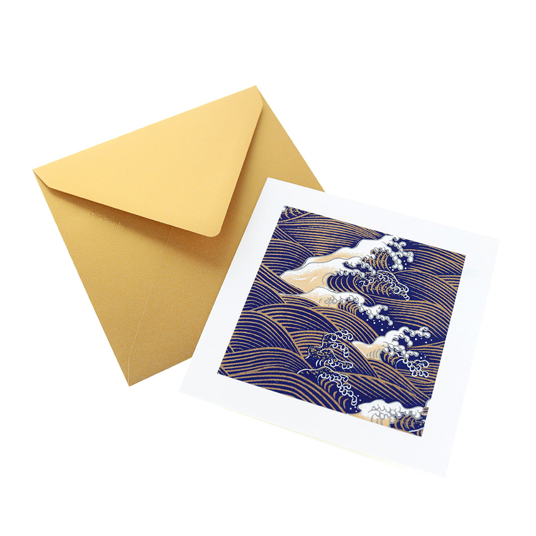 photo packshot vue de face de la carte carrée double habillée d'un carré de papier japonais de 13cm aux motifs de vagues et d'écumes dans les tons bleu nuit, jaune clair et doés (M851) et son enveloppe dorée adeline klam