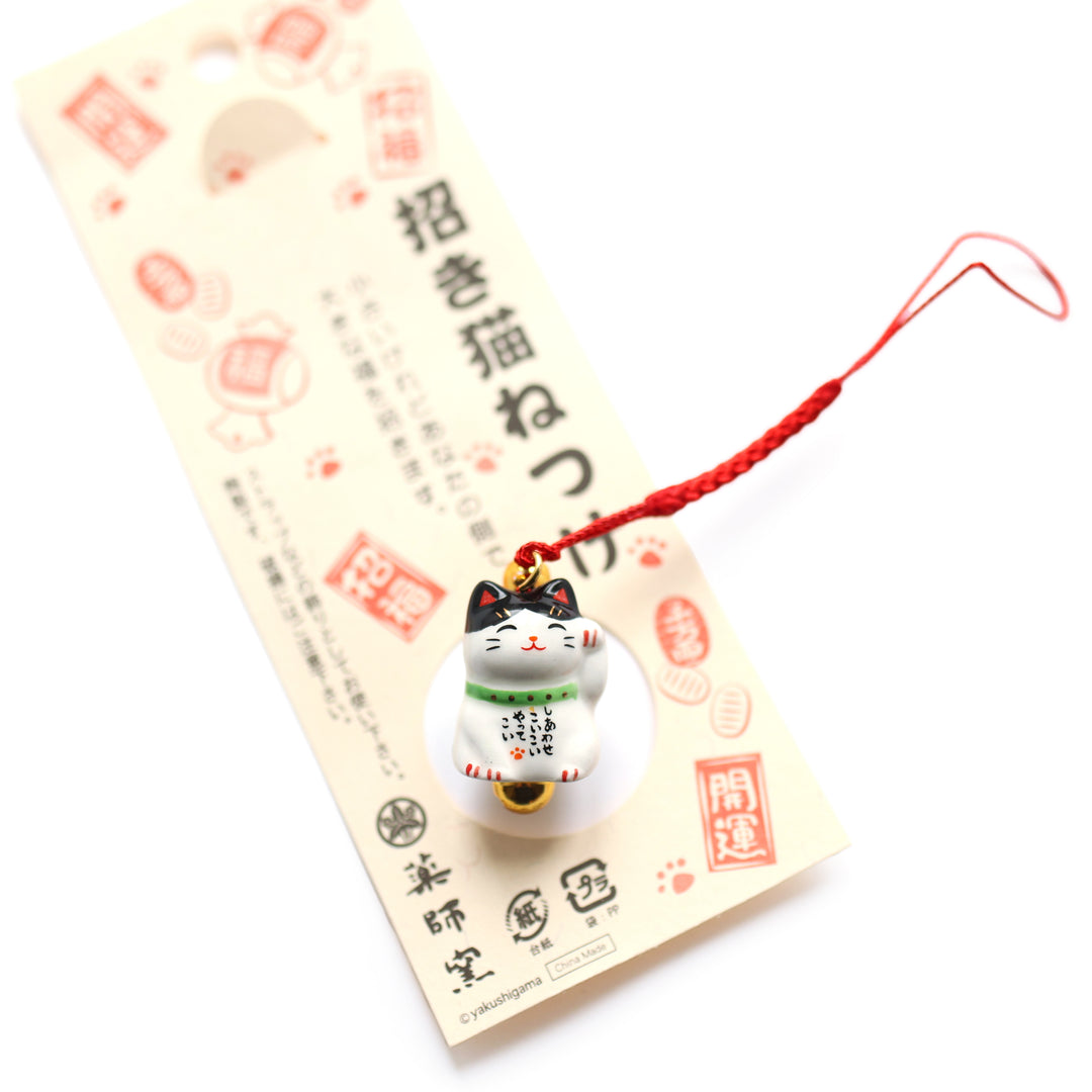 photo packshot du packaging du grigri à suspendre en forme de chat maneki-neko moucheté noir et blanc