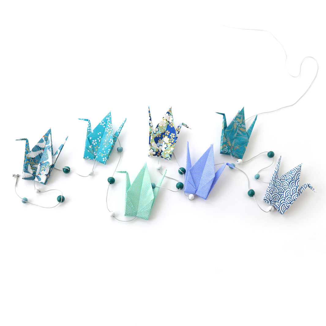 photo packshot de la guirlande montée du kit créatif guirlande de grues en origami « orage » (Z11) dans les tons bleu nuit, bleu canard et vert d'eau adeline klam